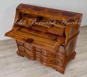 Reproduction of a baroque style chest of drawers with flap shaped in national walnut
