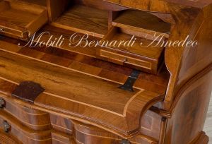Reproduction of a baroque style chest of drawers with flap shaped in national walnut