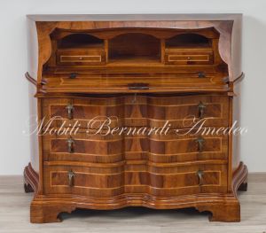 Reproduction of a baroque style chest of drawers with flap shaped in national walnut
