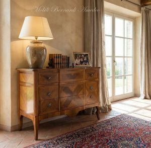 Reproduction of a classic style chest of drawers in inlaid walnut wood placed in a domestic environment