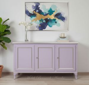 Credenza stile classico in legno massello con finitura colorata lilla e foglia argento ambientata in un soggiorno moderno