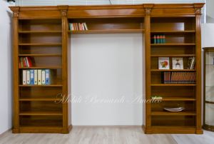 Libreria stile classico a ponte realizzata in legno di noce con capitelli intagliati e ripiani spostabili