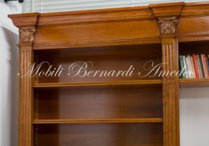 Libreria stile classico a ponte realizzata in legno di noce con capitelli intagliati e ripiani spostabili