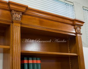 Libreria stile classico a ponte realizzata in legno di noce con capitelli intagliati e ripiani spostabili
