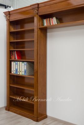 Libreria stile classico a ponte realizzata in legno di noce con capitelli intagliati e ripiani spostabili
