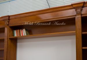 Libreria stile classico a ponte realizzata in legno di noce con capitelli intagliati e ripiani spostabili