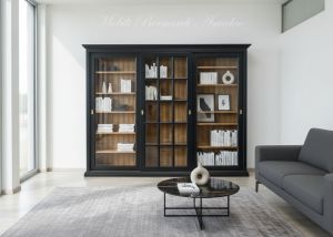 Vetrina libreria inserita in un soggiorno moderno realizzata in legno con 3 ante scorrevoli con vetro