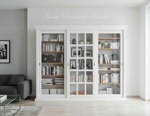 Vetrina libreria inserita in un soggiorno moderno realizzata in legno con 3 ante scorrevoli finitura colore bianco