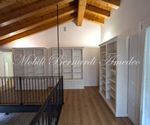 Librerie colore bianco produzione artigiale inserite in una casa moderna con pavimento e tetto in legno