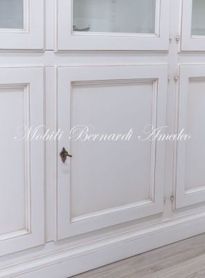 Grande libreria classica con ante a vetro realizzata artigianalmente in legno massello con finitura colore bianco anticato