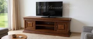 Mobile basso da soggiorno per Tv in legno massiccio con intarsi e intaglio stile classico posizionato in una casa moderna