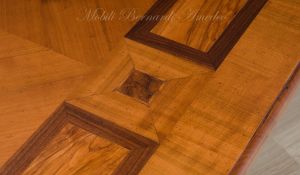 Tavolo in stile classico realizzato in legno massello e intarsiato in ciliegio ulivo e noce con gambe laccate colore bianco