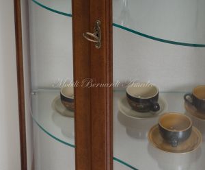Vetrina sagomata in legno stile classico con schienale tappezzato e ripiani in vetro